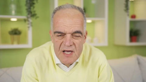 Frustrated and grumpy old man looking at camera at home. Video stock 235623469