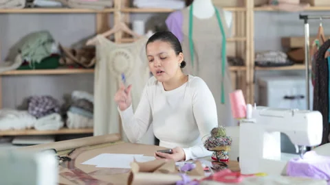 Frustrated and puzzled dressmaker with documents in her hands stands in front of Stock Footage 320451037