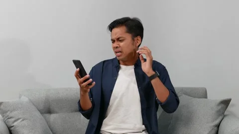 Frustrated Asian young man using smartphone in home, error and disconnected Stock Footage 332782769