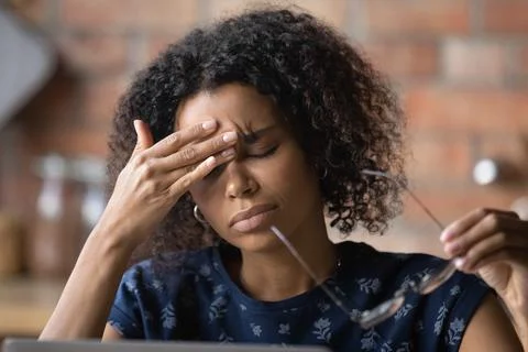 Frustrated black female freelancer overworked by computer feel headache migraine Stock Photos