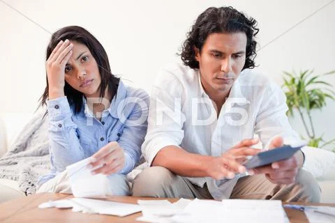 Frustrated couple doing their calculations in the living room Stock Photos