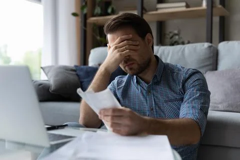 Frustrated desperate millennial man checking bills for payments Stock-Fotos