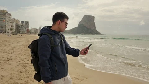 Frustrated digital nomad having a difficult video meeting on the beach 動画素材 333690477