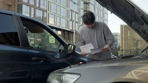 The frustrated driver of the crashed vehicle is trying to assess the damage by Stock Footage 310457858