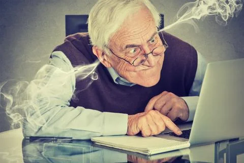 Frustrated elderly old man using laptop computer sitting at table Stock Photos