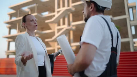 Frustrated female architect arguing with a construction worker holding blue.. Stock Footage 341333820