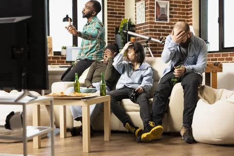 Frustrated friends on sofa React to Gaming Defeat Stock Photos