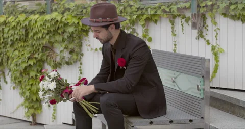A frustrated guy after a date sitting in the park for a cigarette 스톡 동영상 145430940