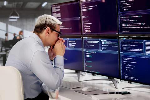 Frustrated Male Developer Struggling With Complex Web Code At Office Desk 库存照片