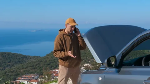 Frustrated man calling for help with a broken down car on a road trip Video stock 331777831