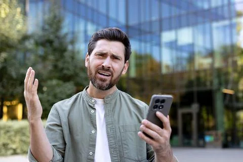 Frustrated man having connection problems with smartphone outdoors Stock-Fotos