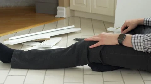 Frustrated man looks at watch while assembling flat pack furniture Stock Footage 56071210