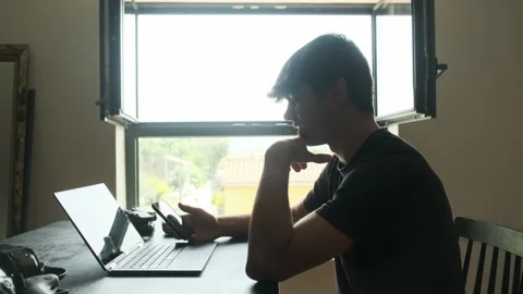 Frustrated man scrolling instagram while editing a video. Silhouette Stock Footage 243426178