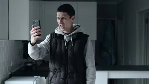 Frustrated man shouting during video call in kitchen, emotional argument at home Stock-Footage 309187945