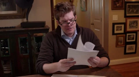 Frustrated man sitting down throwing papers and forms on a table Stock Footage 49190160