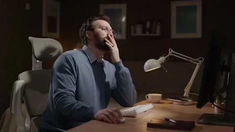Frustrated man stares at computer screen and places his palm over his face as Video stock 337645401