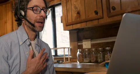 Frustrated man talking on a headset to a customer while working in his home Stock Footage 128177366