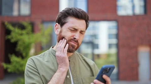 Frustrated Man With Toothache Using Smartphone Outdoors and Experiencing Pain Stock-Footage 308689365