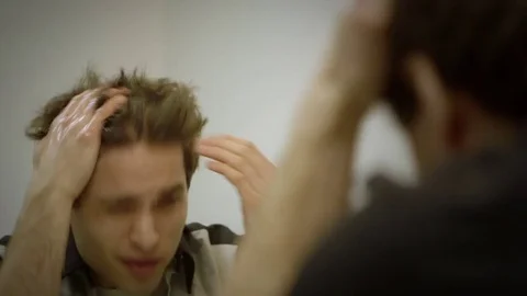 A frustrated man tries to fix his messy hair in the mirror. Stock-Footage 70084209