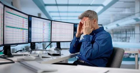 Frustrated Man Using Multiple Data Sets On Computer Spreadsheet At Work. Pote 库存照片