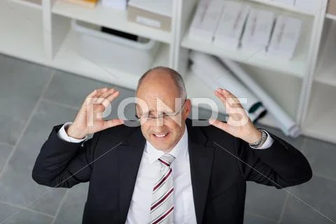Frustrated mature businessman raising arms in office Stock Photos