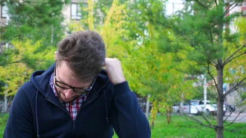 Frustrated middle-aged man sitting in the Park. Beard and glasses, slow-mo 스톡 동영상 95160107