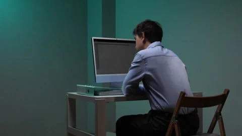 Frustrated office worker throws up his hands at a cluttered desk, staring at a 動画素材 345530392