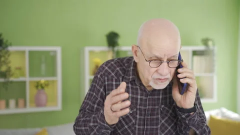 Frustrated old man talking on the phone is at home. Video stock 232240508