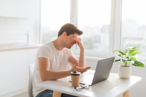 Frustrated with problems young man working on laptop computer at home Stock Photos