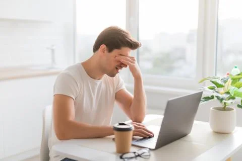 Frustrated with problems young man working on laptop computer at home Stock Photos