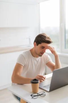 Frustrated with problems young man working on laptop computer at home 库存照片
