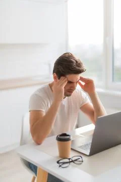 Frustrated with problems young man working on laptop computer at home Stock Photos