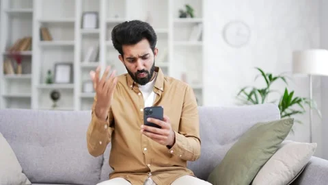 Frustrated stressed handsome bearded man reads bad news on a smartphone while  Stock Footage 252201705