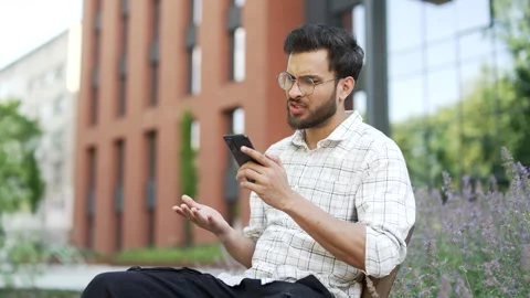 Frustrated stressed young man read bad news on mobile phone while sitting  Stock Footage 301116098
