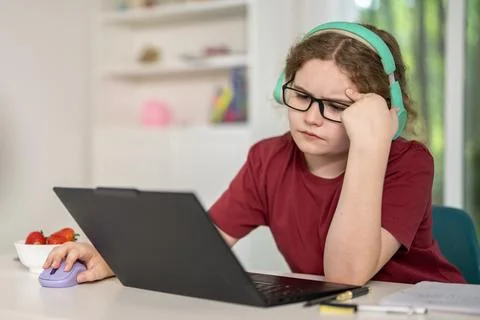 Frustrated student uses computer headset. Frustrated child studies online today Stock Photos