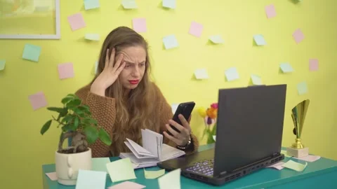 Frustrated woman multitasking Checking the phone and shaking head in frustration Stock Footage 306650175