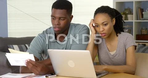Frustrated Young Black Couple Going Over Bills And Finances Online