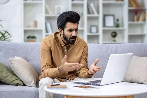 Frustrated young man with beard experiencing computer problems working from home 库存照片