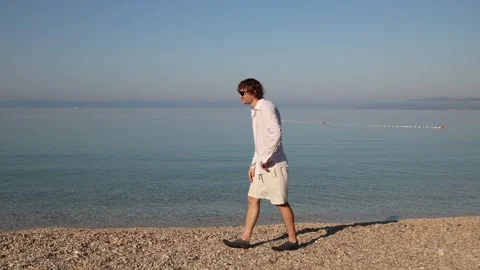 Frustrated young man feels bored by the sea and wishes he could return home Видео 341622799