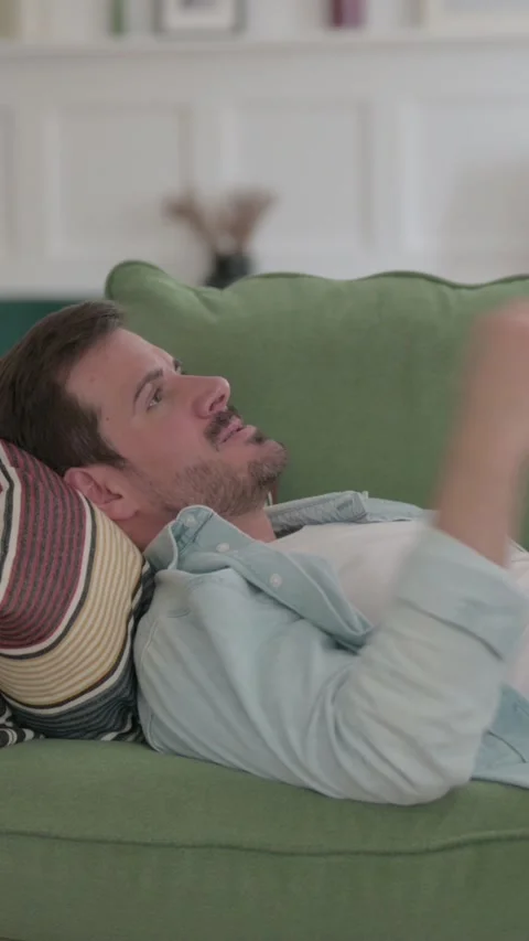 Frustrated Young Man Lying on Sofa in Stress, Vertical Video Stock Footage 328970892