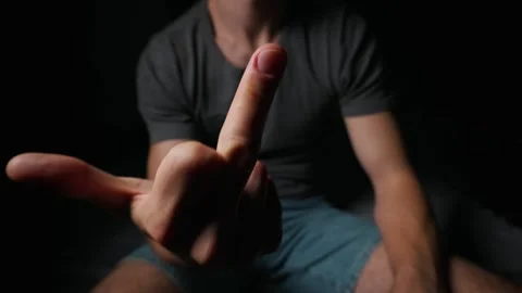 Frustrated Young Man Showing Offensive Middle Finger Gesture in Dark Room Stock Footage 339366263