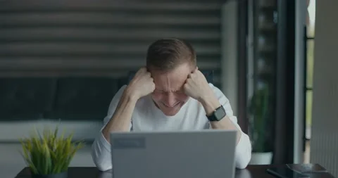 Frustrated young man sitting in front of his laptop after seeing big mistake he Stock Footage 197618490