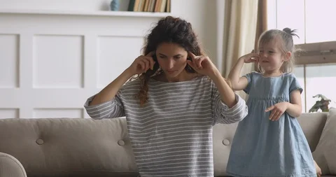Frustrated young nanny babysitter plugging ears, ignoring loud kid girl. Stock Footage 125536730
