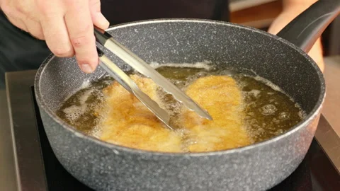 Fry 2 schnitzel in a pan with clarified butter. The cook turns the cutlets so Stock Footage 163049147