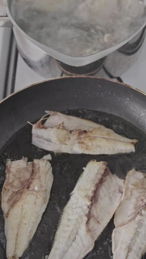 Fry and flip white fish in a frying pan with a spatula Stock Footage 328253239