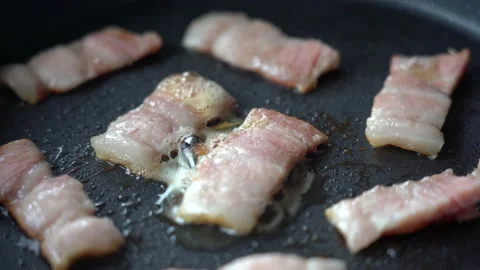 Fry the bacon pieces in a pan. Crispy pieces of delicious bacon are fried in a Stock Footage 141316332