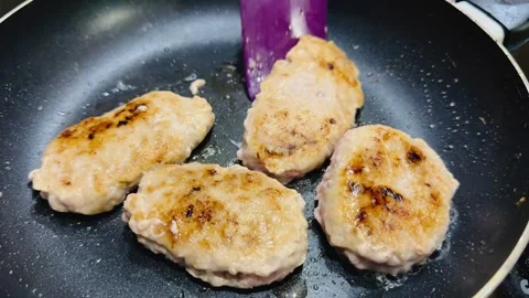 Fry the cutlets in a frying pan and stir with a purple spatula. 库存影片 253736418