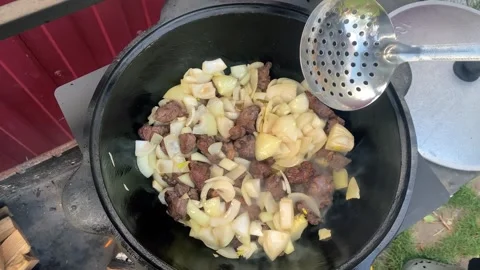 Fry the meat and onions in vegetable oil in a cast iron cauldron on a wire rack Stock Footage 278601080