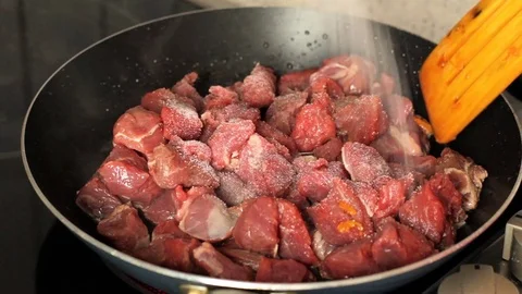 Fry pieces of meat in a frying pan. Meat in a frying pan sprinkle with salt and Stock Footage