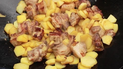 Fry potatoes with meat on a fire in a giant frying pan on a summer sunny day, cl Stock Footage 136569901